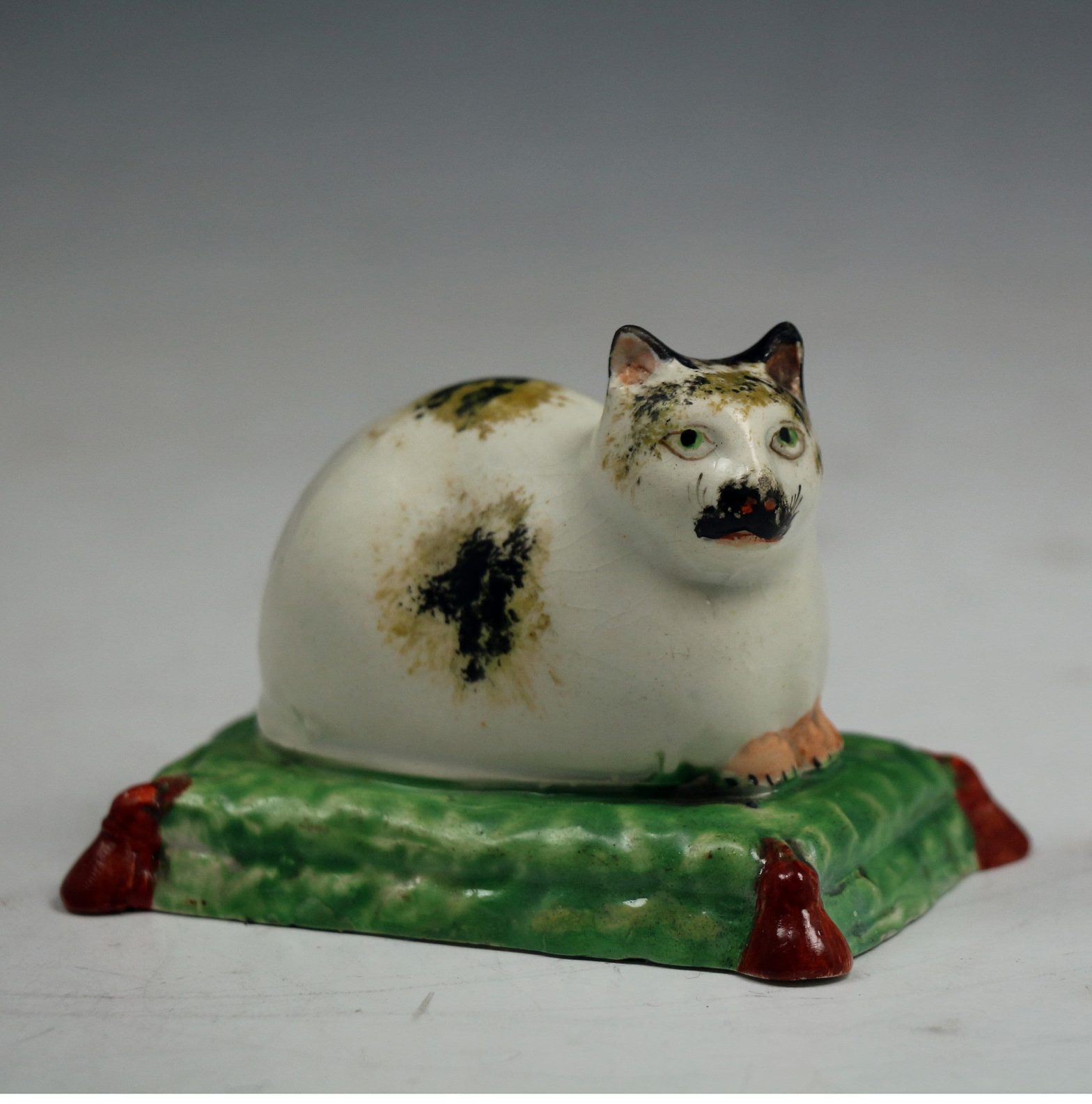 Staffordshire pearlware pottery figure of a reclining cat on a cushion ...