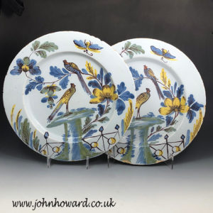 A pair of Delftware pottery chargers from the Bristol Delftworks of two birds in a garden setting 18th century England