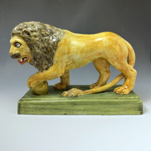 Large scale Prattware figure of a lion foot resting on a sphere  England circa 1800