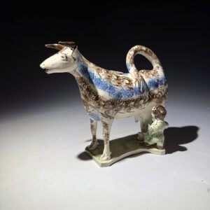 English pottery cow creamer with brown and blue sponge decoration c1800
